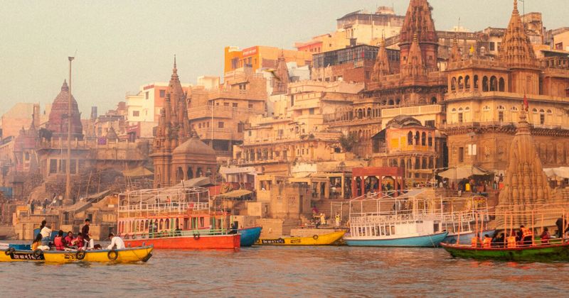 Varanasi ghats from the Ganges at golden hour — the 6.5-kilometre riverfront in late afternoon light, the city's most visually complete view and the perspective from which the 84 ghats can be understood as a single continuous sacred space rather than a series of individual destinations