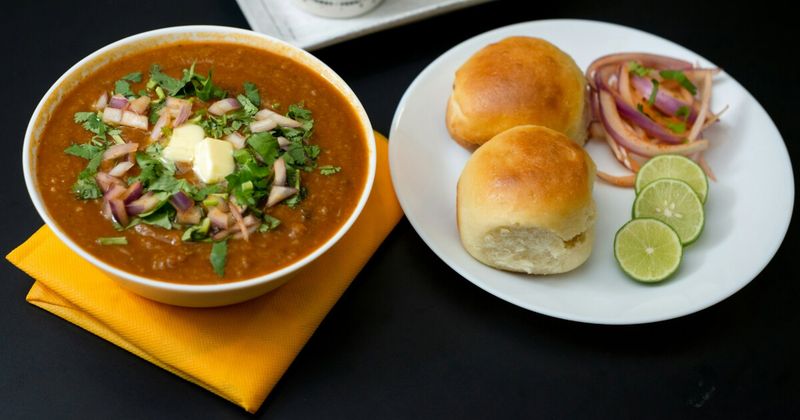 Warm, butter-toasted pav bread rolls served on a white plate, ready to be dipped into a spicy Mumbai Pav Bhaji.
