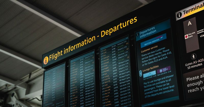 Airport departure board showing international flight times — USA to India flight booking guide 2026