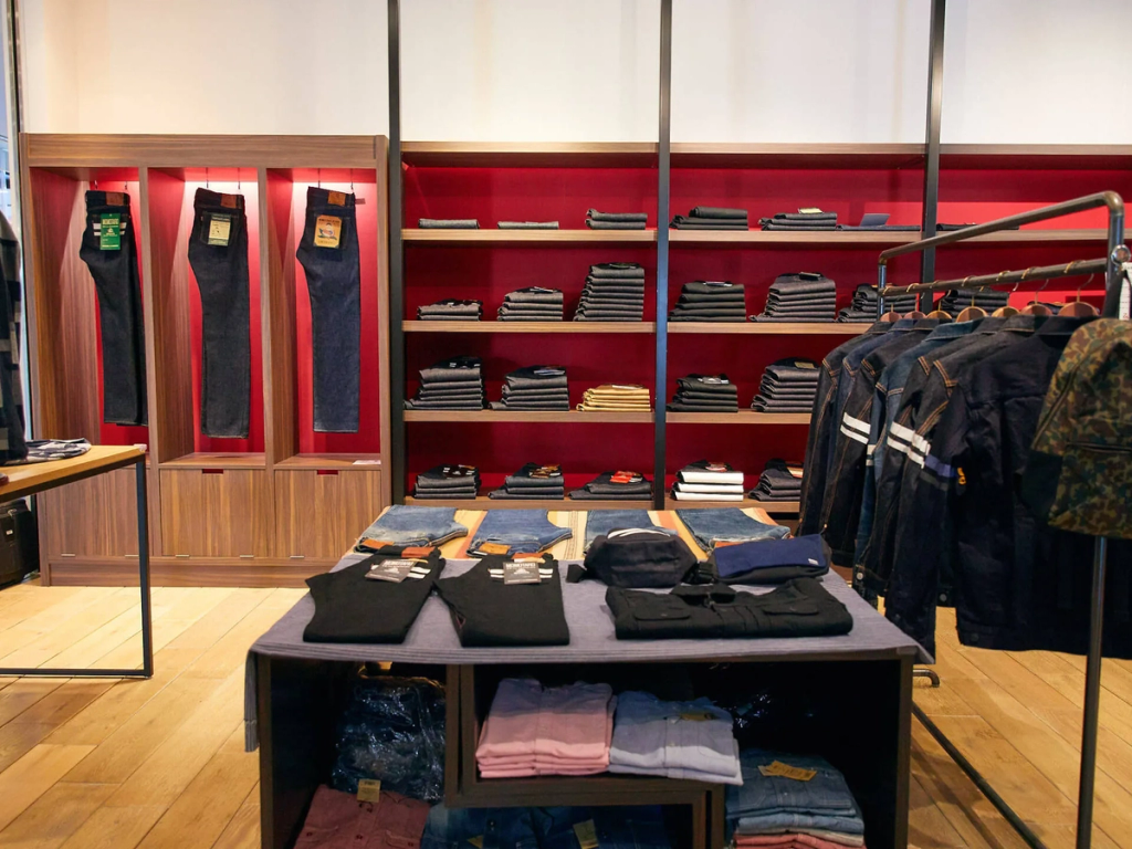 Denim retail display with red backdrop shelving.