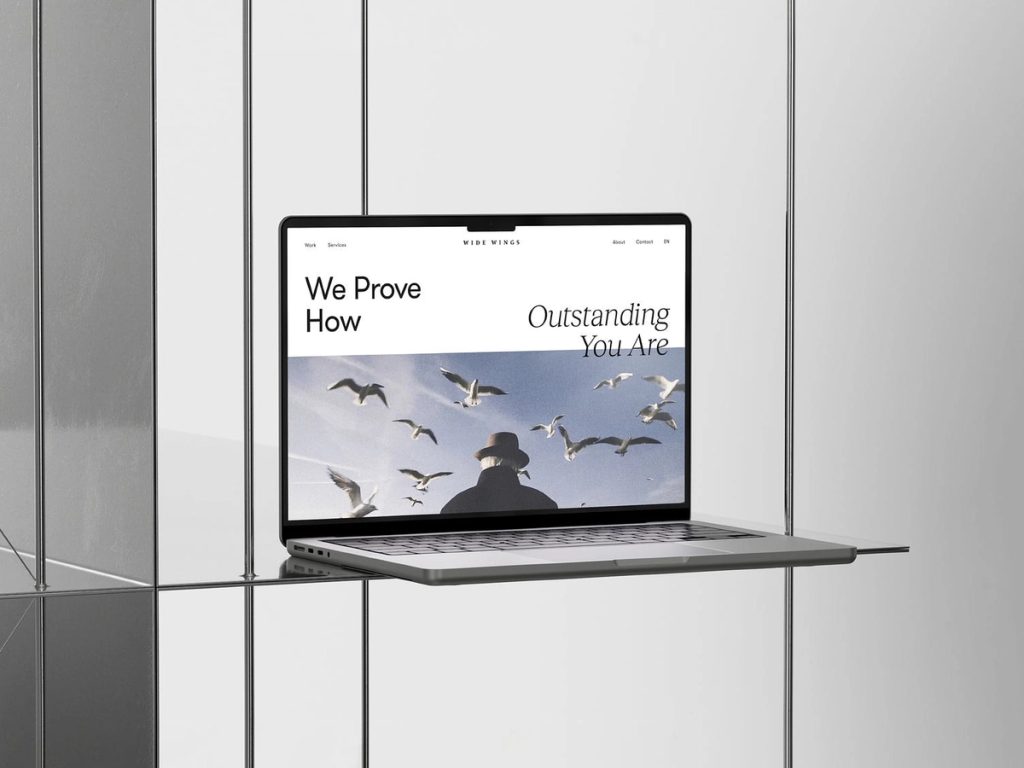 Laptop displaying "Wide Wings" website with birds in flight.