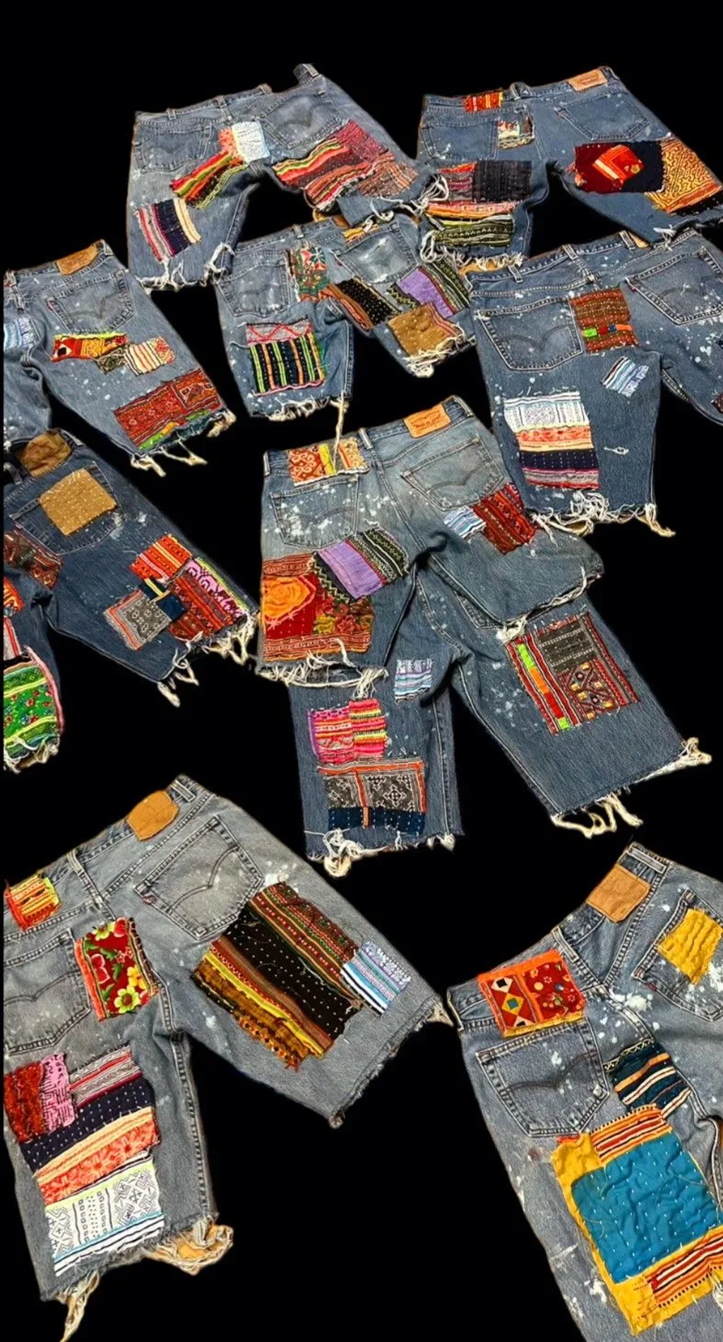 Distressed denim shorts featuring colorful fabric patches in various patterns and textiles, displayed against a black background.