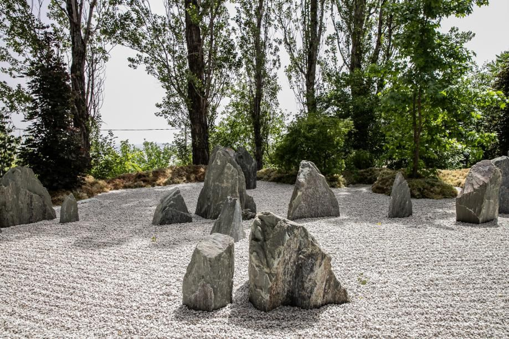 Zen rock garden with standing stones surrounded by trees.