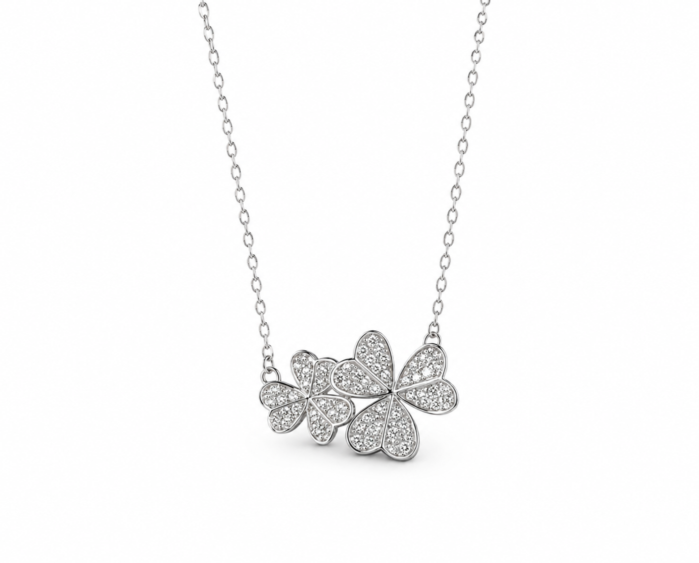 Two overlapping diamond-set flower motifs in white-toned gold, suspended from a fine chain in the supplied image
