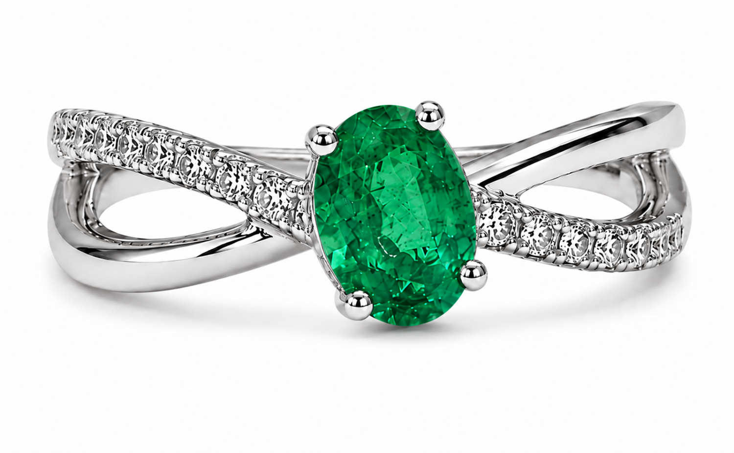 Oval emerald in a four-claw setting above polished and natural diamond-set crossover shoulders in 18k white gold
