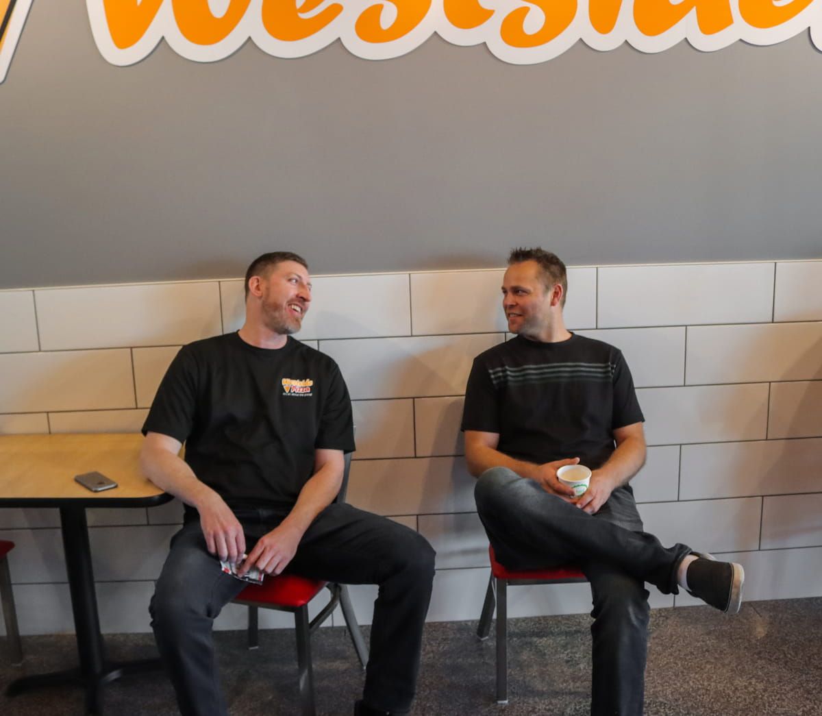Two people sitting at a westside pizza location, talking