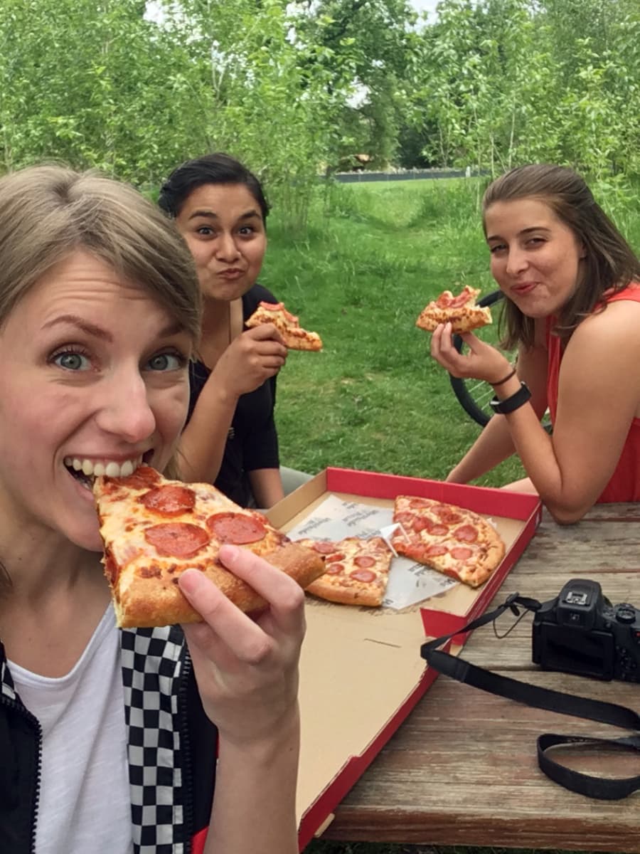 Three people enjoying a Westside Pizza at a park bench