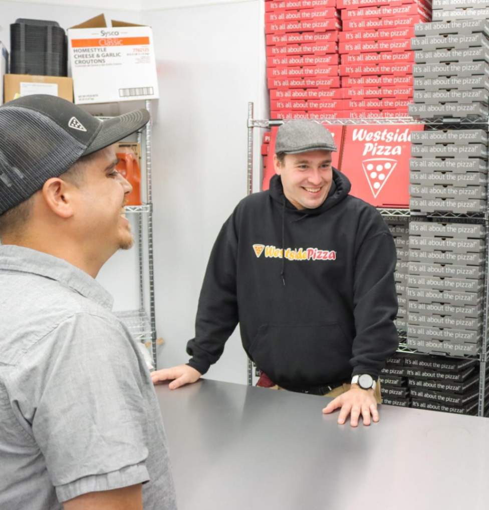 Person standing in front of pizza boxes, at a counter