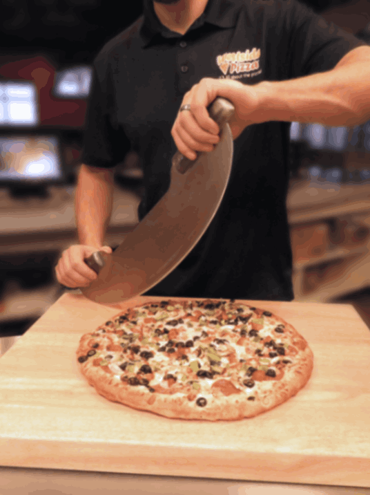 A Westside Pizza employee cutting a pizza