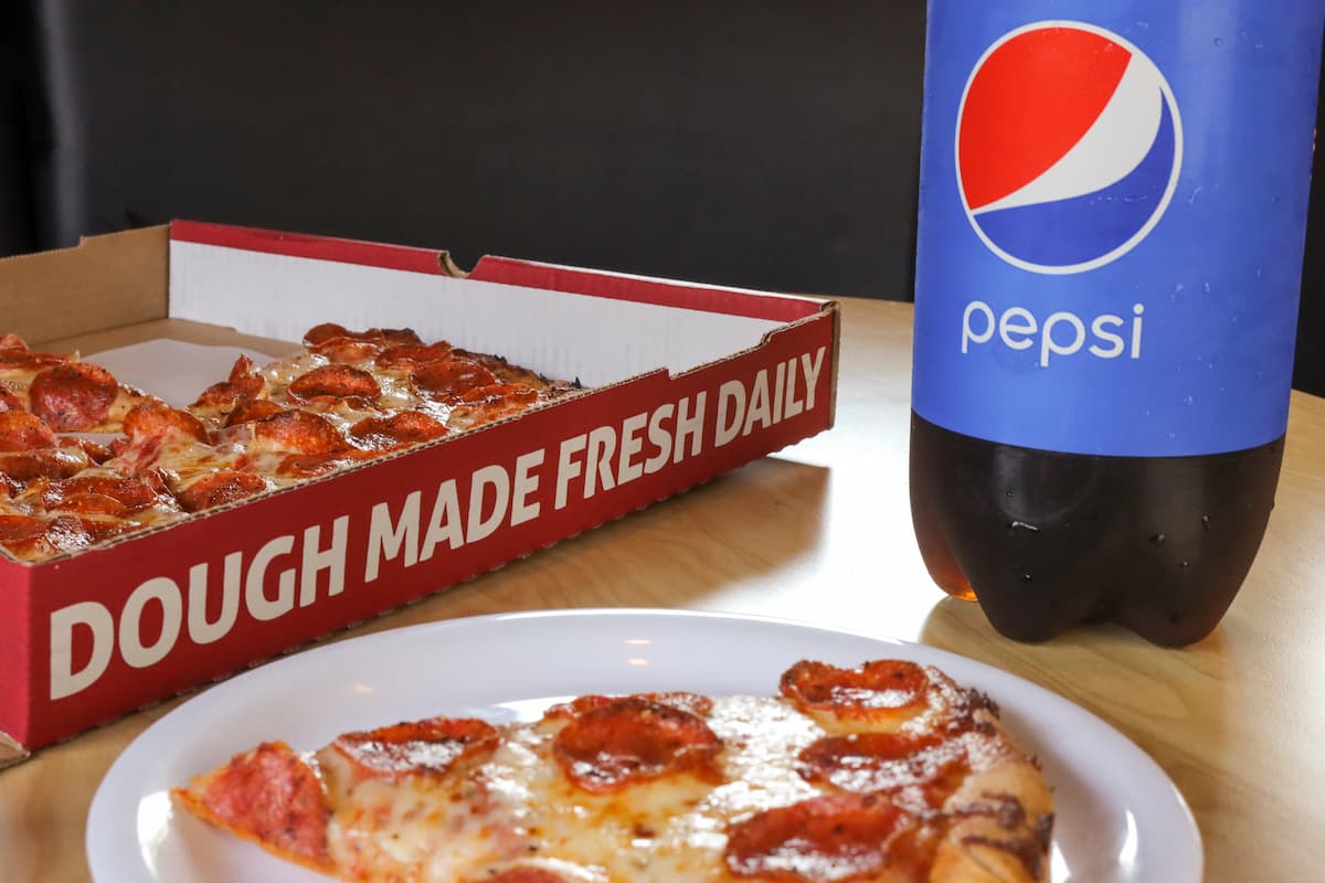 A recyclable Westside pizza box with a pepsi bottle and a plate.