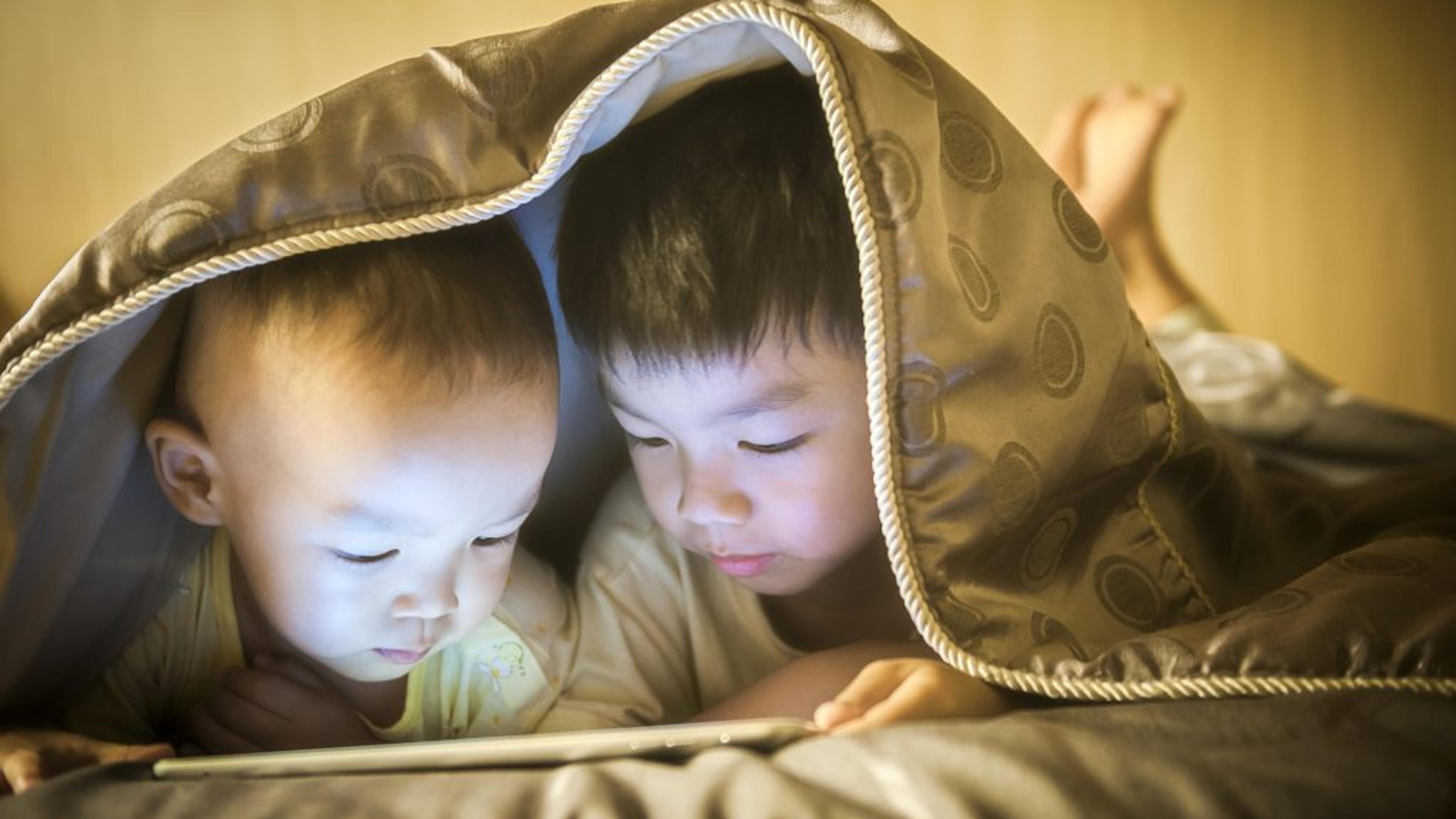 Two children reading under a quilt