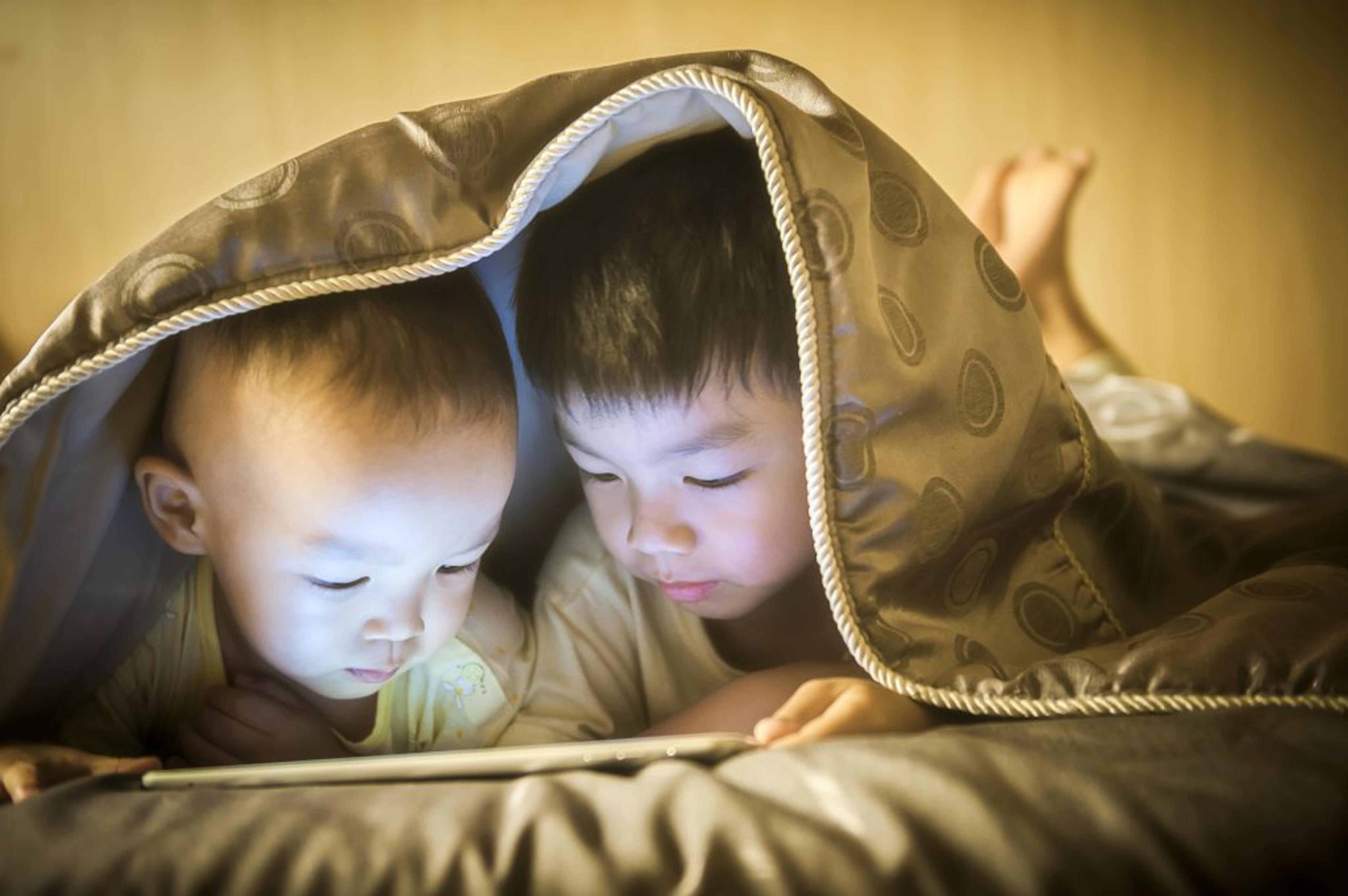 Two children reading under a quilt