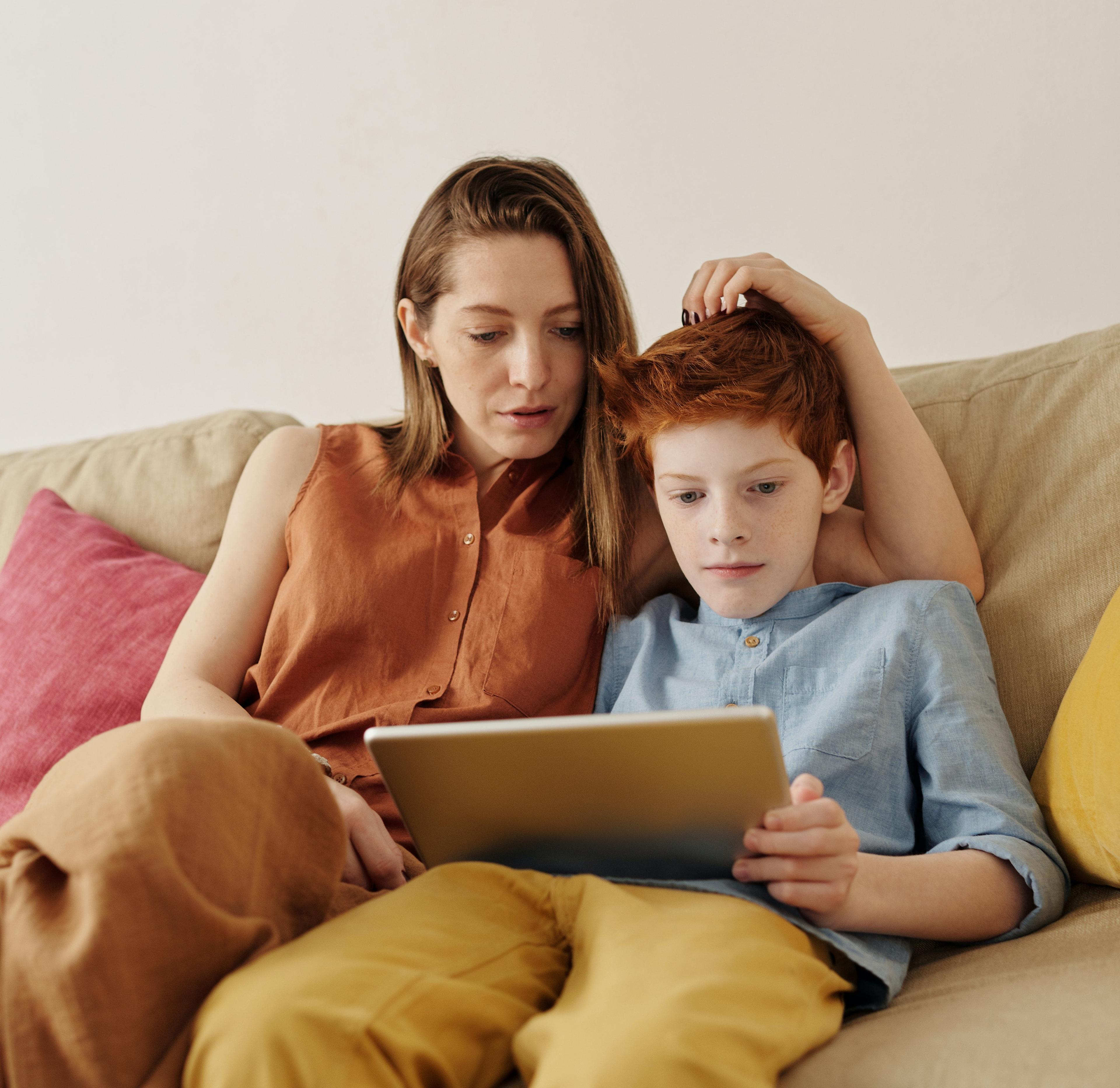 Mamma och son sitter i soffan och läser från appen