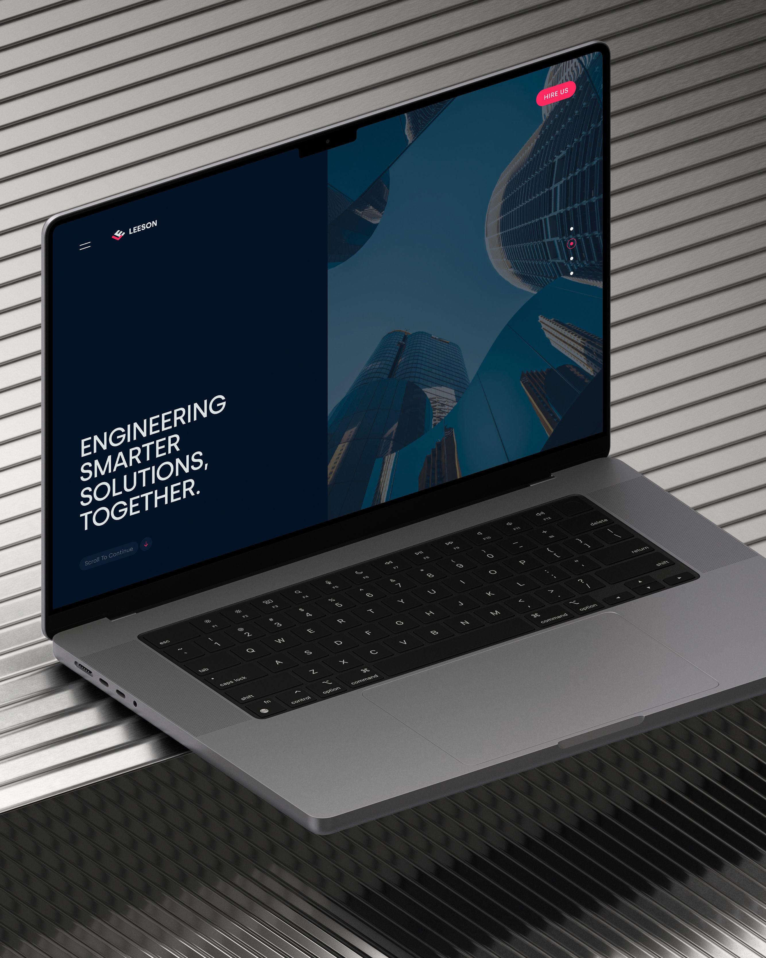 Leeson Engineering website homepage on a laptop, showing the hero headline “Engineering Smarter Solutions, Together.” on a dark navy panel beside an upward view of glass skyscrapers, with a pink Hire Us button in the corner.