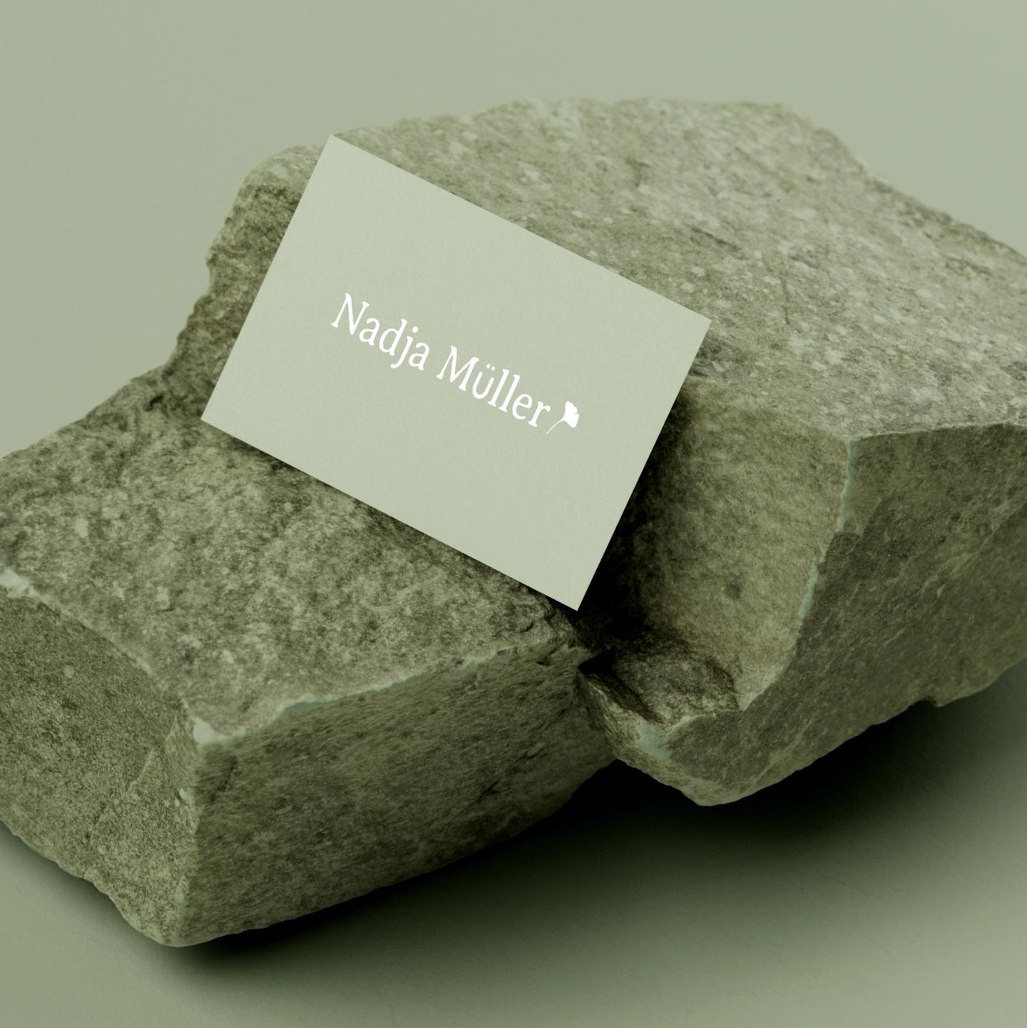 Elegant business card with the name 'Nadja Müller' placed on a stone surface, showcasing minimalistic design.
