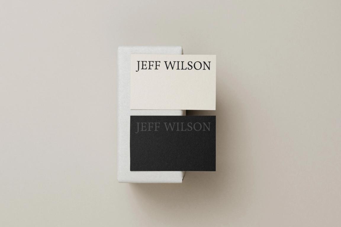 Minimalist business cards with elegant typography for 'Jeff Wilson' in black and cream colors, showcasing modern branding design.