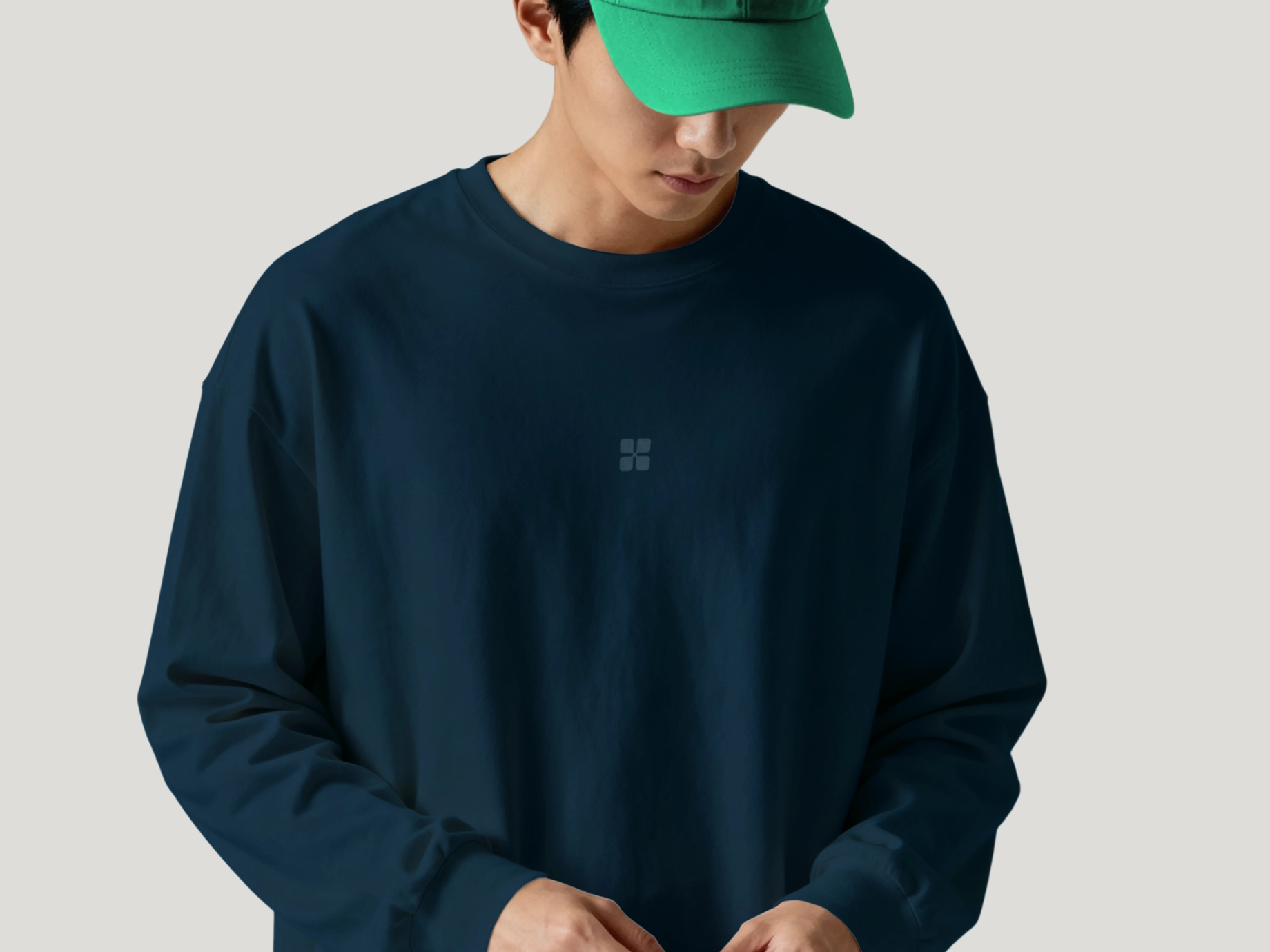 Person wearing a navy sweatshirt with a small Havium logo on the chest and a bright green cap against a light grey background.