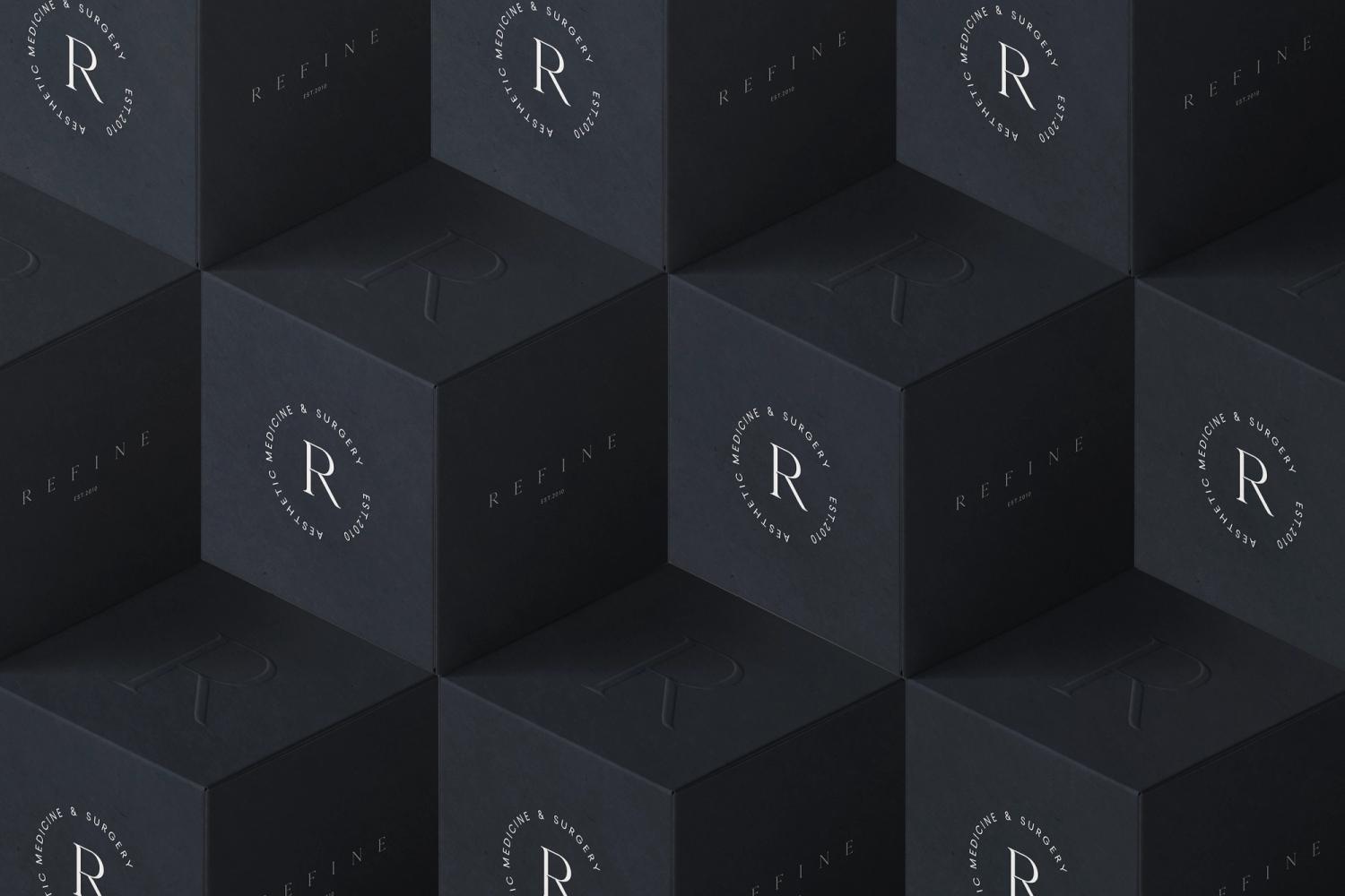 Refine branding design displayed on black boxes with embossed 'R' logo, showcasing luxury aesthetics for a medical and surgical business.