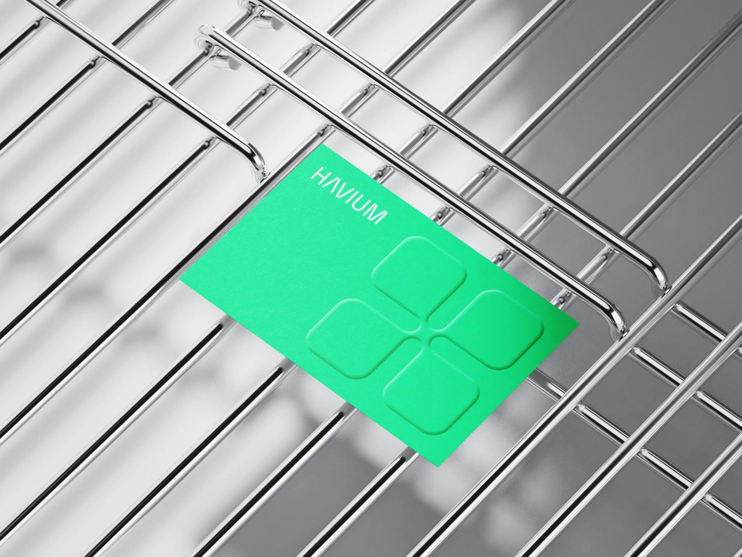 Close-up of Haviium's modern, minimalist business card with a green background and embossed geometric design.
