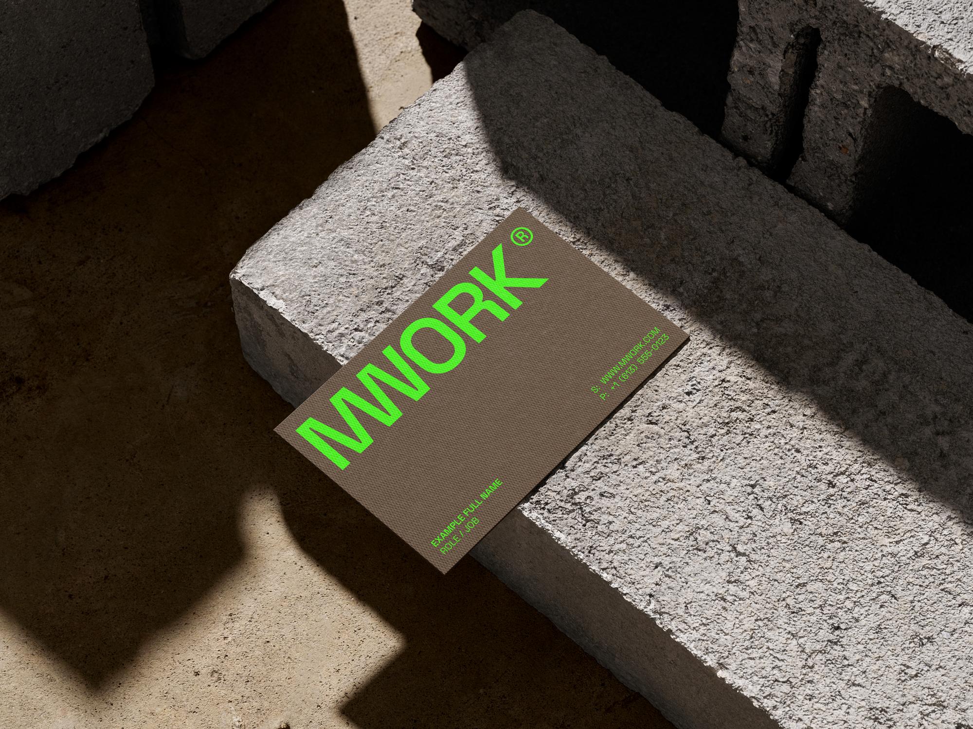 Minimalistic business card with bold "MWORK" logo in neon green, placed on a concrete surface.