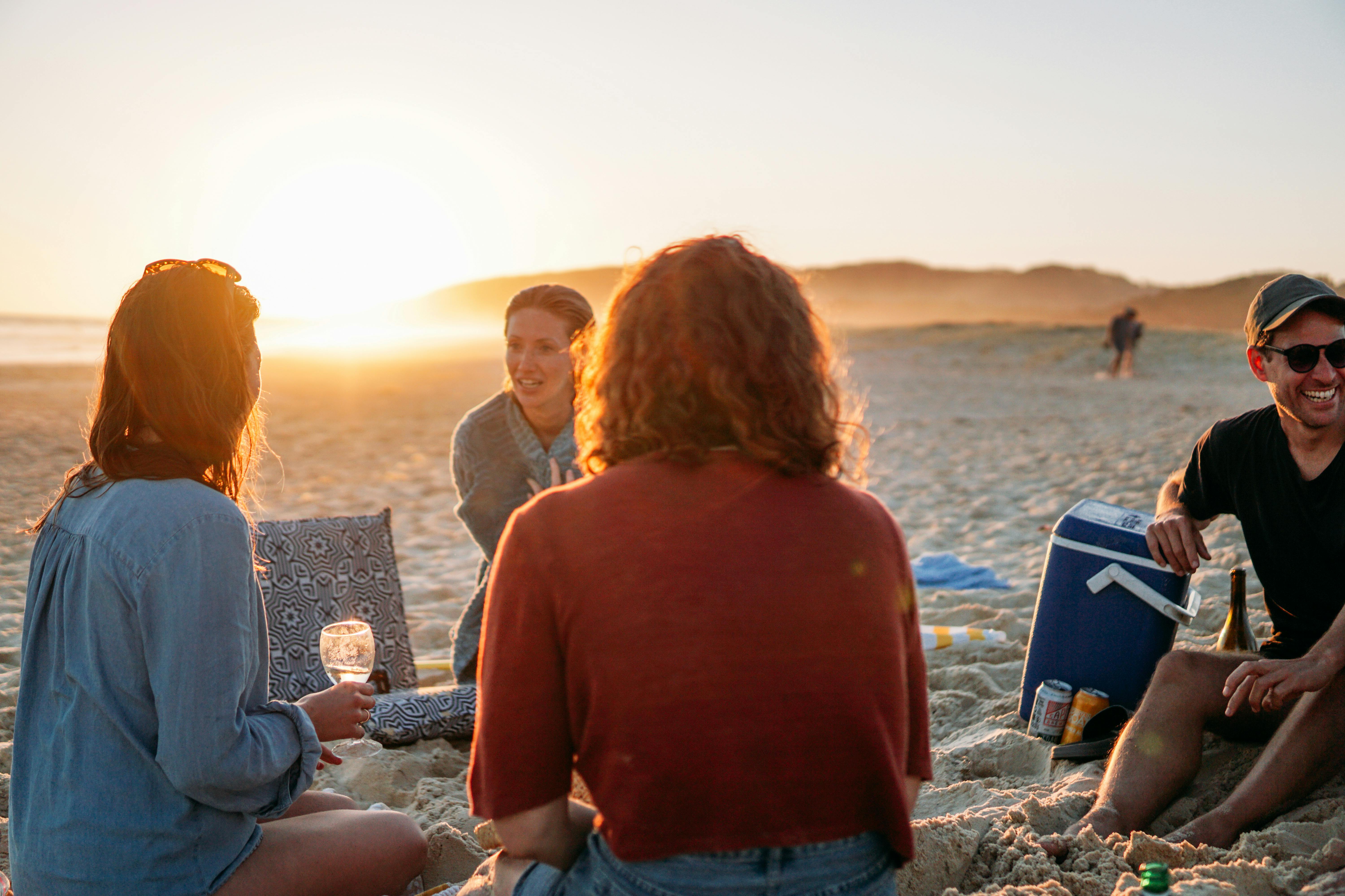 Gruppe von Menschen sitzt am Strand und unterhält sich