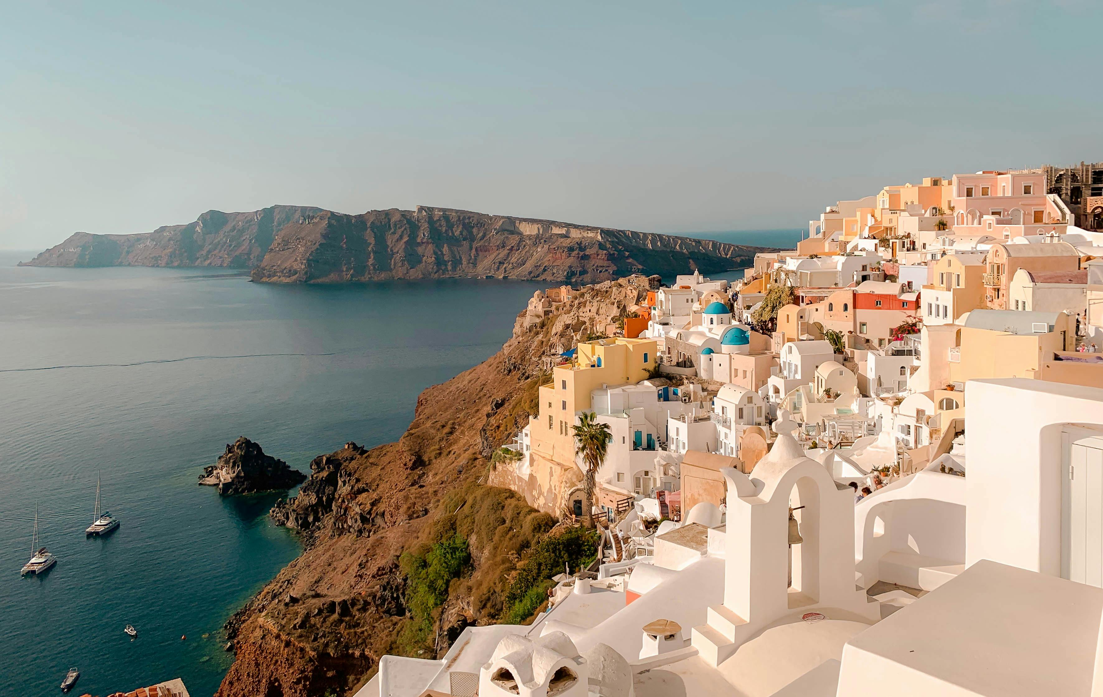 griechische Insel als Urlaubsziel, viele Häuser mit blauen Dächern und sonnige Umgebung mit Blick aufs Meer.