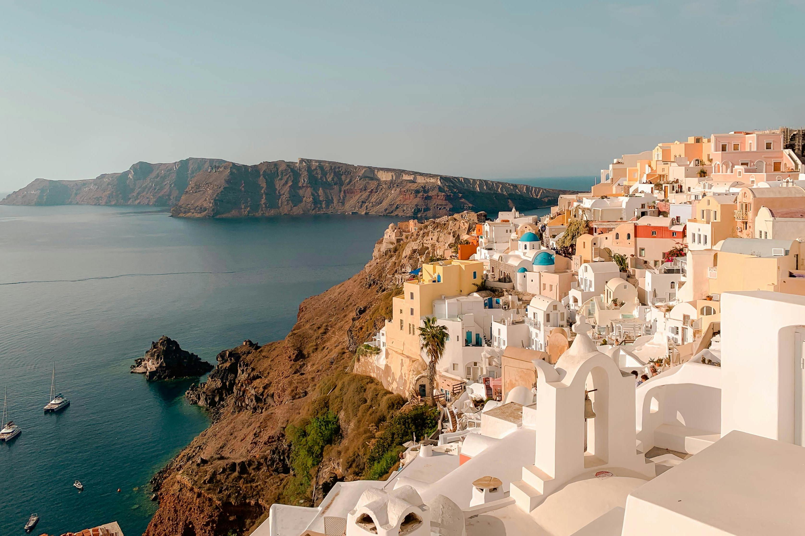griechische Insel als Urlaubsziel, viele Häuser mit blauen Dächern und sonnige Umgebung mit Blick aufs Meer.