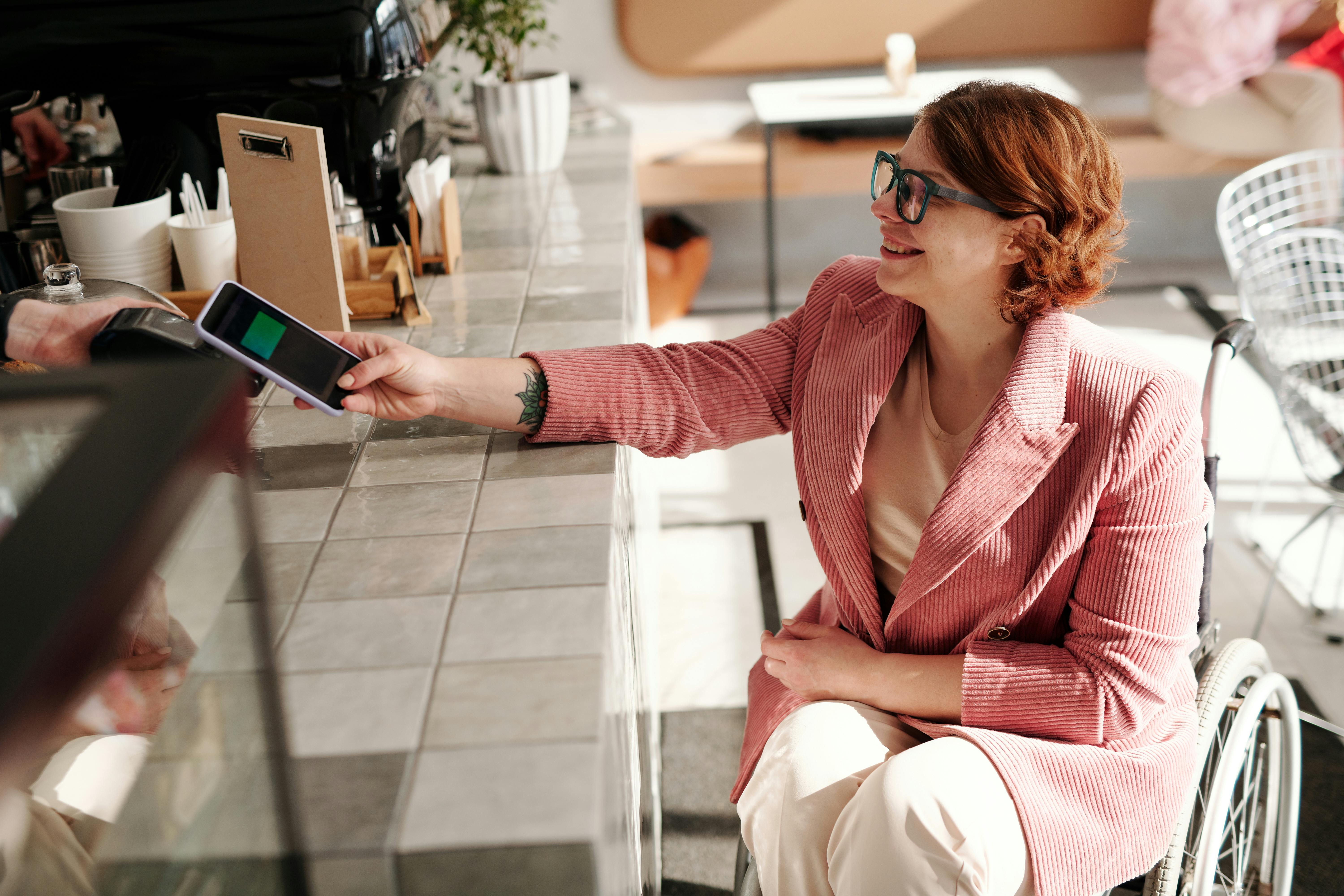 Frau bezahlt kontaktlos mit Smartphone an einem Kassenterminal