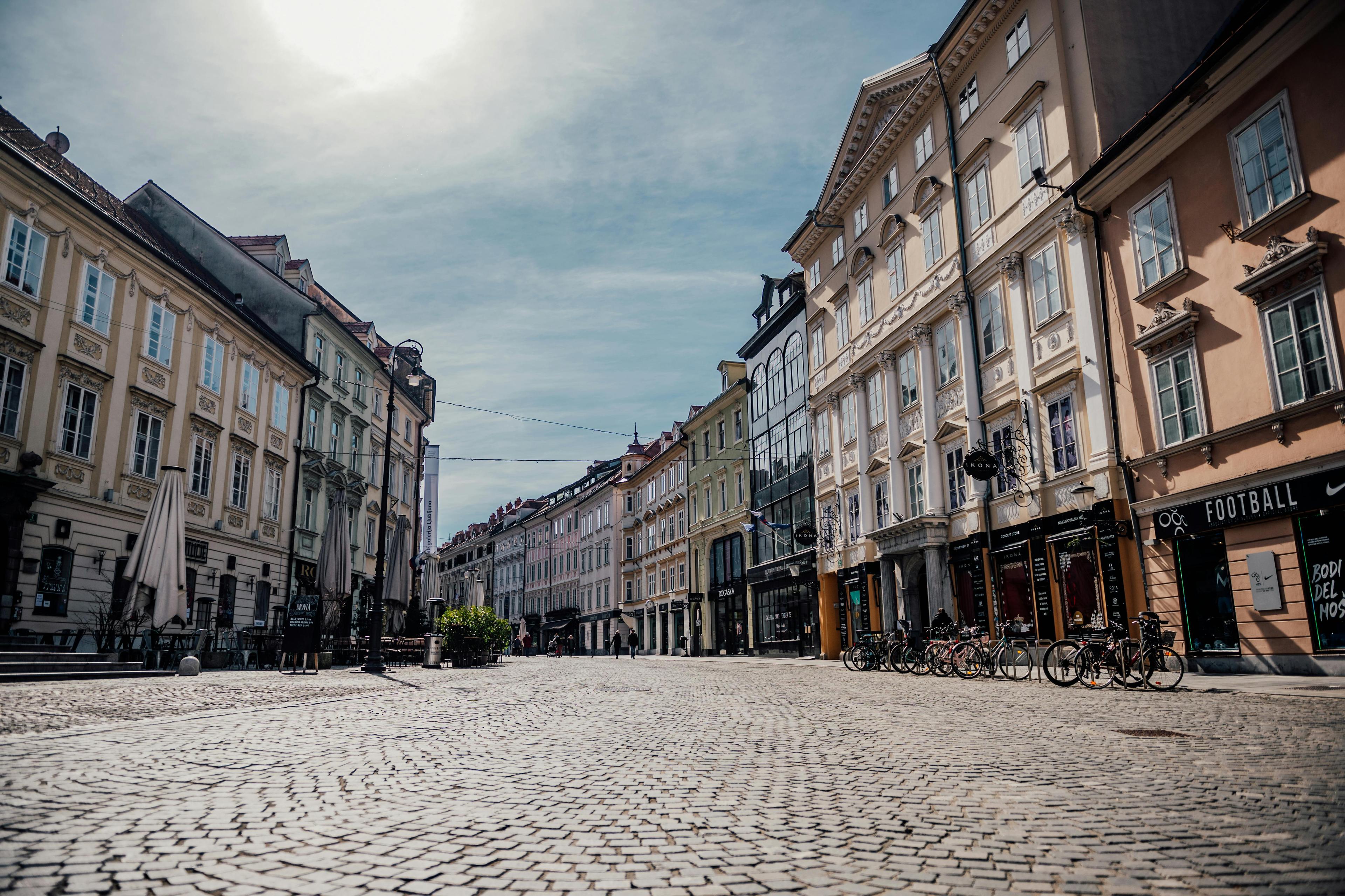 Pflastersteingasse in einer europäischen Altstadt mit historischen Gebäuden und bewölktem Himmel.