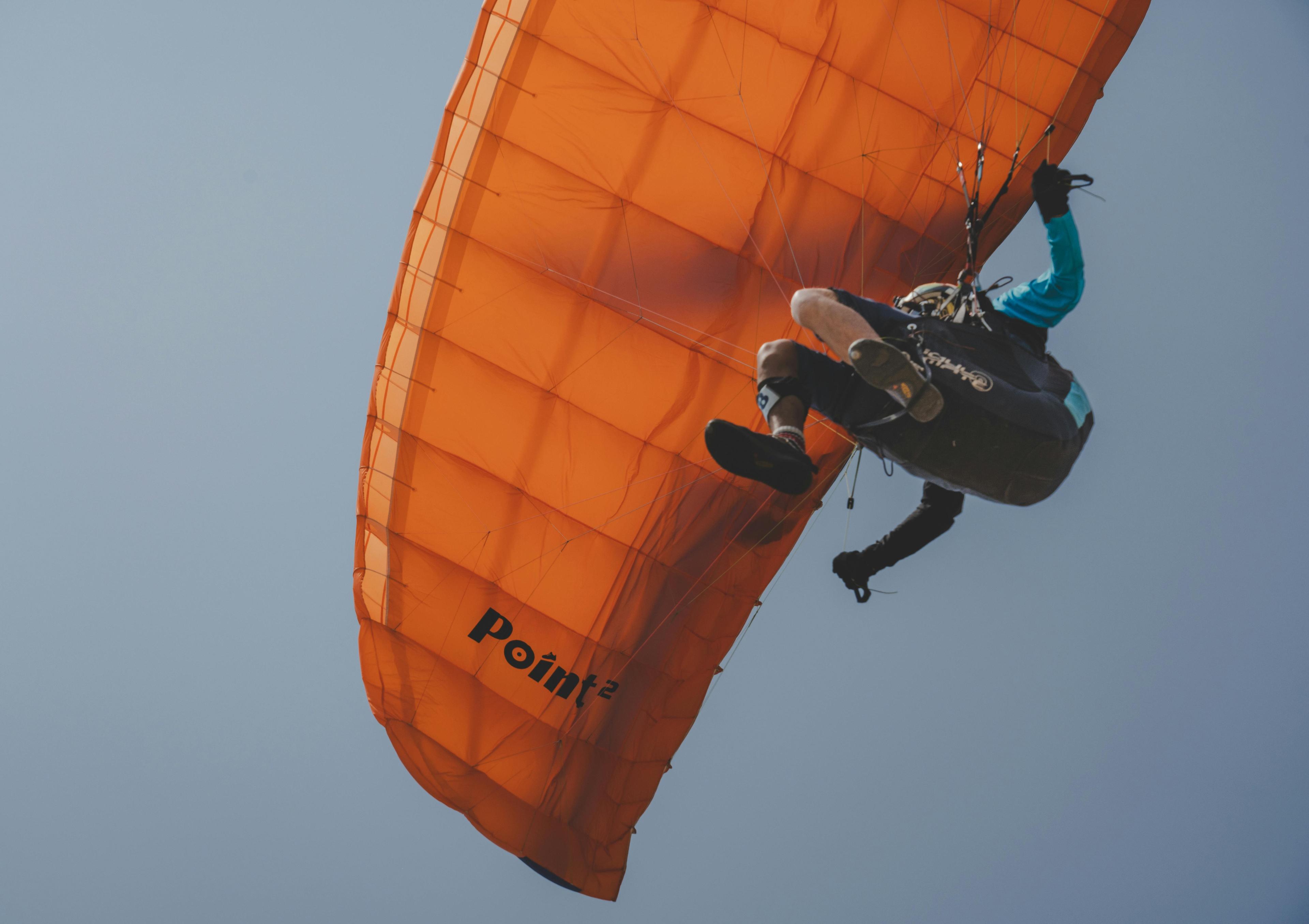 Person gleitet beim Paragliding über eine Landschaft, aufgenommen in der Luft.