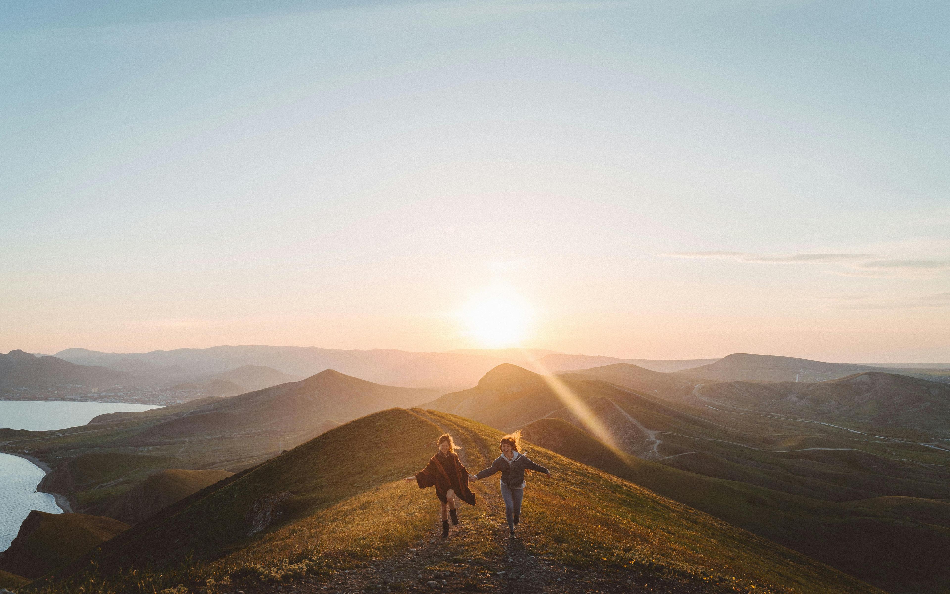 Personen wandern auf einem Hügel bei Sonnenuntergang