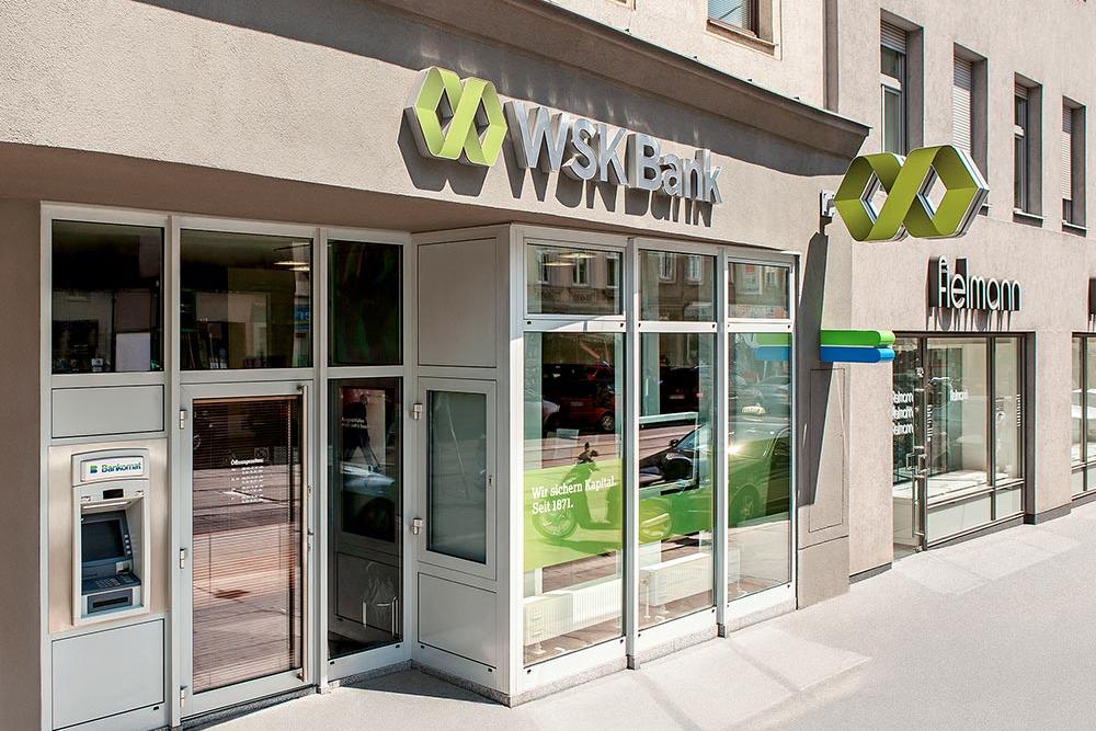 Eingangsbereich der WSK-Bank-Filiale Thaliastraße mit Geldautomat und großem Banklogo an der Gebäudefassade.
