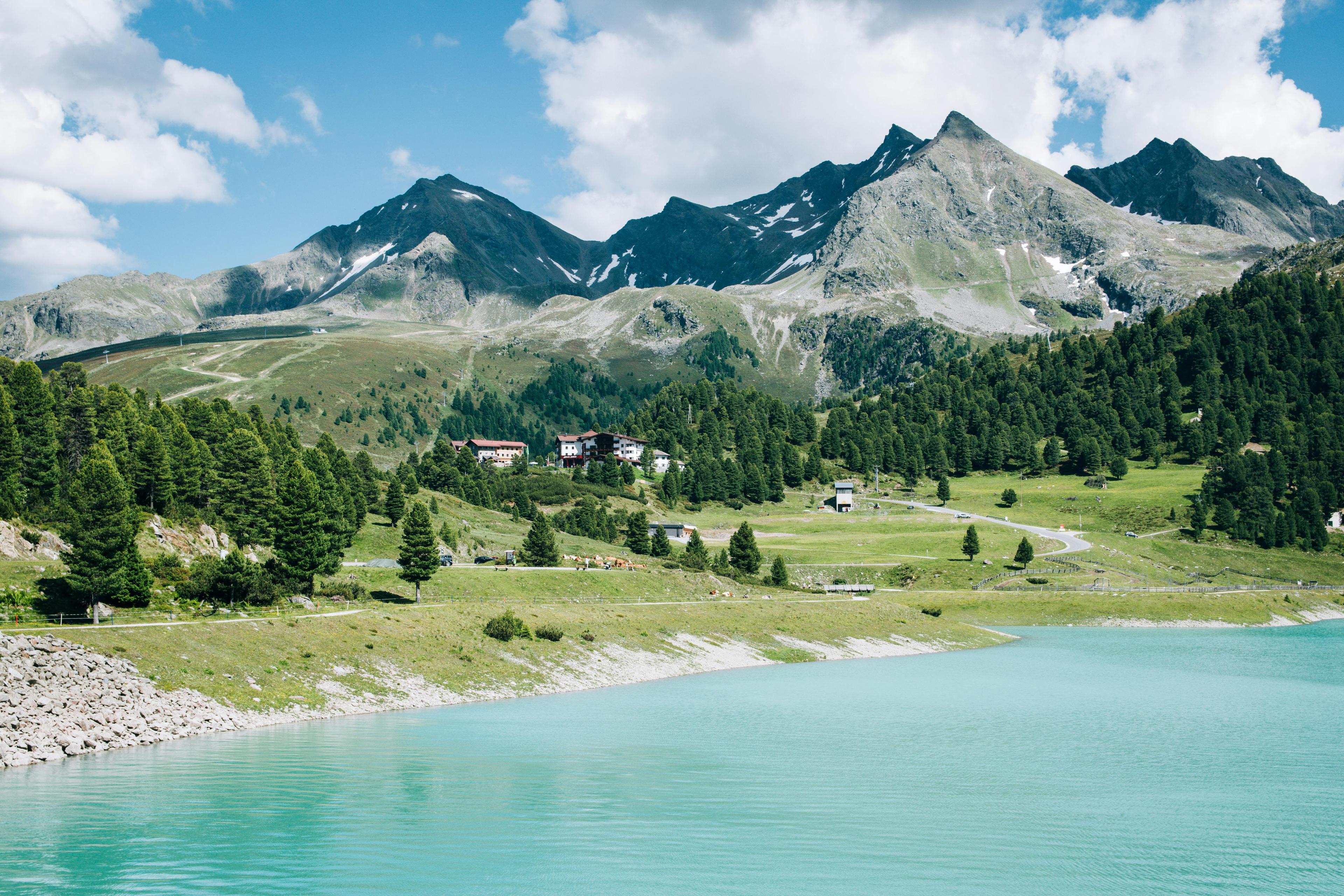 Wandertraum: Türkises Wasser im Vordergrund und hohe Berge im Hintergrund.
