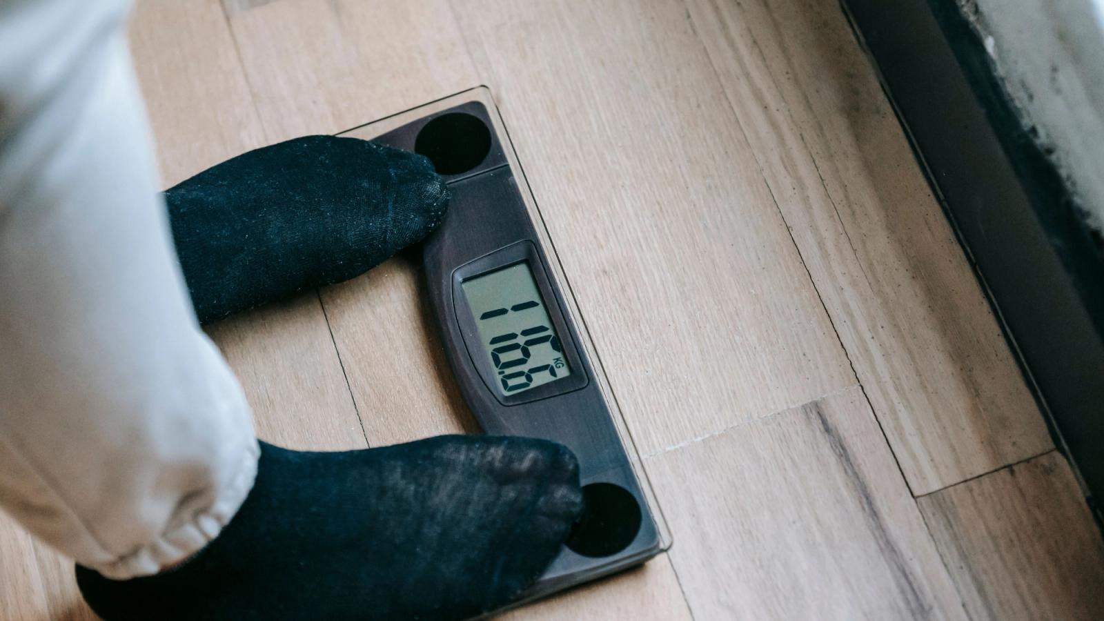 Person weighing themselves on a digital bathroom scale to track weight