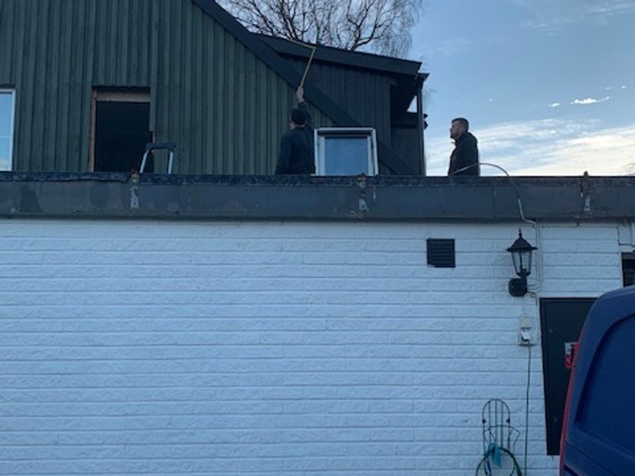 Pågående takarbete på svart hus med arbetare