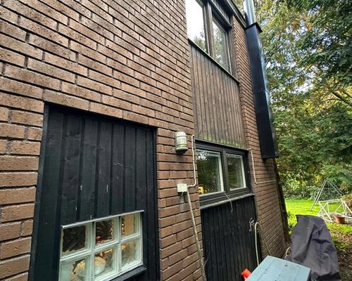 Husets hörn före renoveringen med tegel, mörk panel och garageport