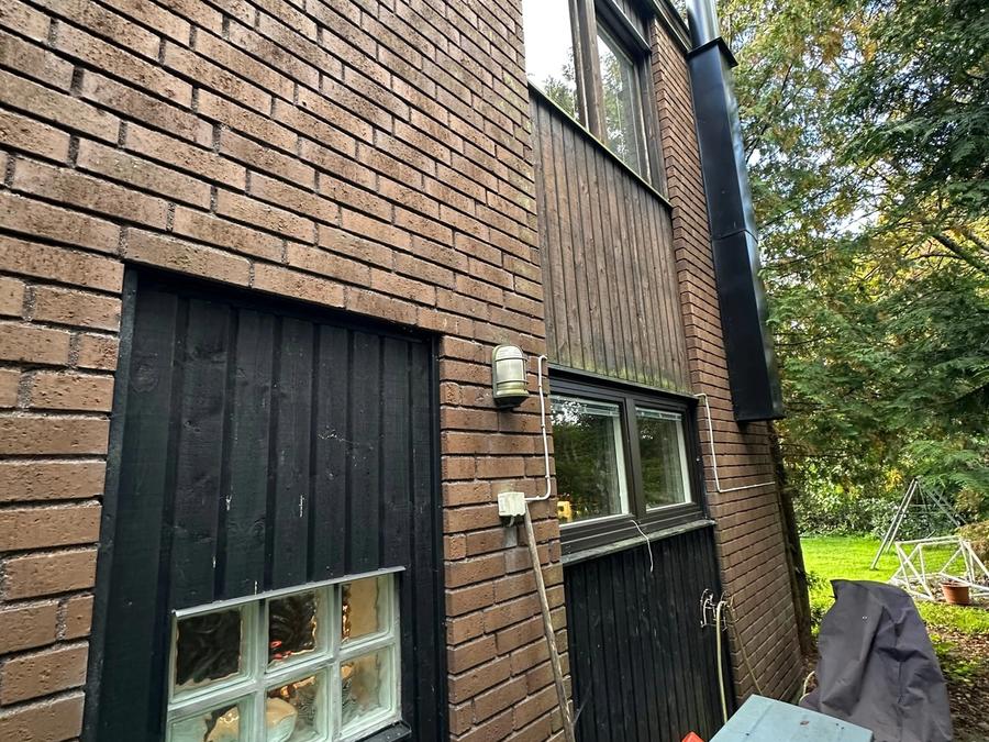 Husets hörn före renoveringen med tegel, mörk panel och garageport