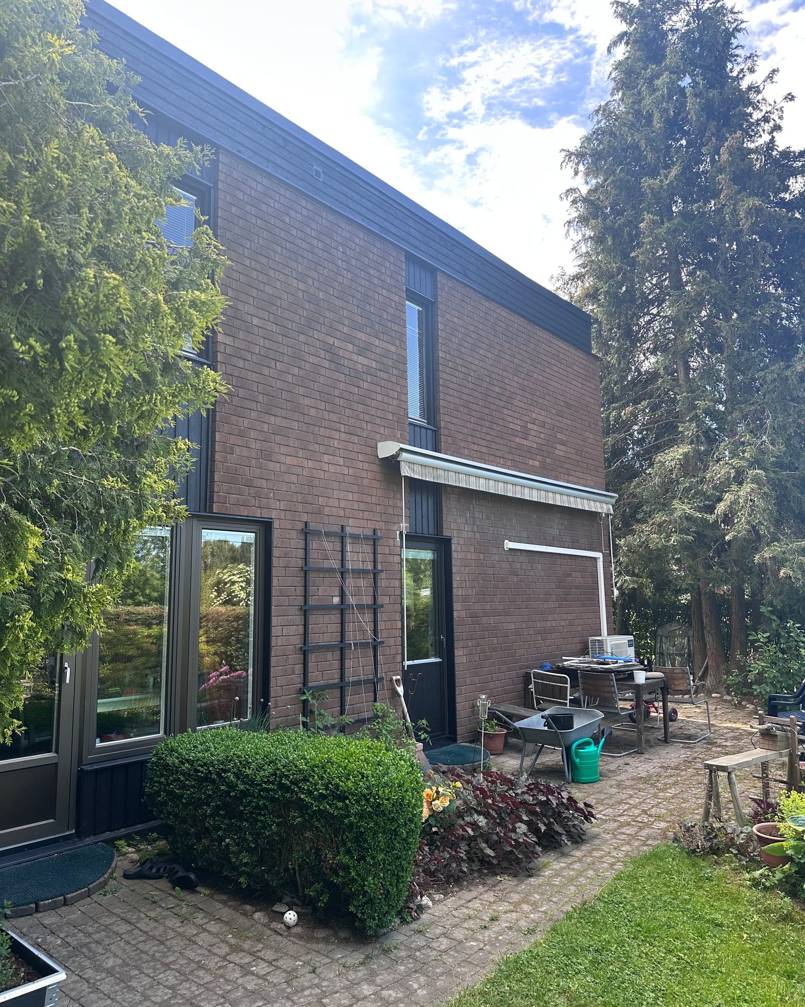 Renoverat hus i Hässelby en sommardag, brunt tegel och nymålad mörk träpanel