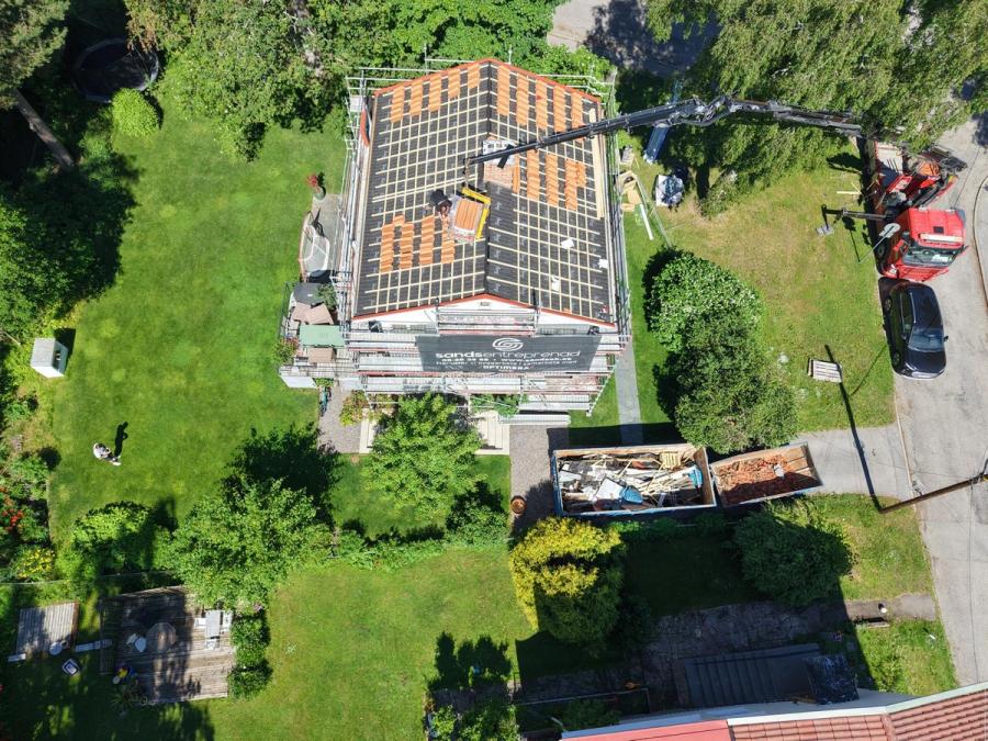 Takstommen med ny läkt och Sands Entreprenads banderoll på ställningen