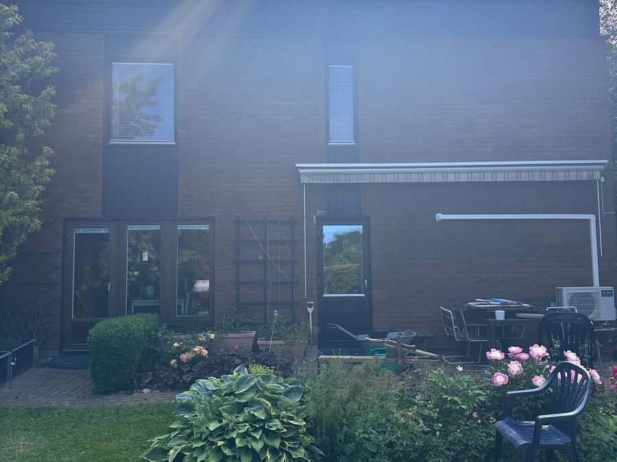 Husets baksida efter renoveringen med nymålad panel och trädgård i sommarskrud