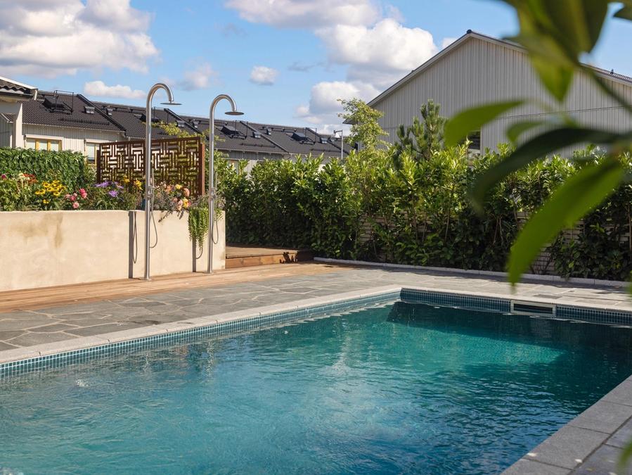 Poolen en sommardag med utedusch och grönska runt om