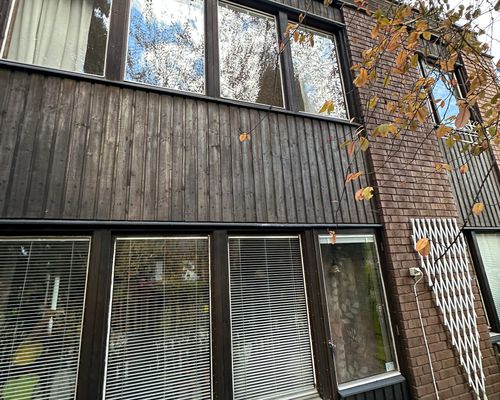 Gamla mörka träpaneler på fasaden, slitna och väderbrutna