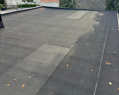 Gammalt spräckt papptak före renovering, tydliga sprickor och slitage