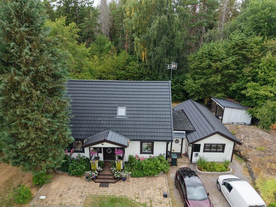 Villa i Flen efter takomläggning, hela taket och uthuset med nya svarta betongpannor
