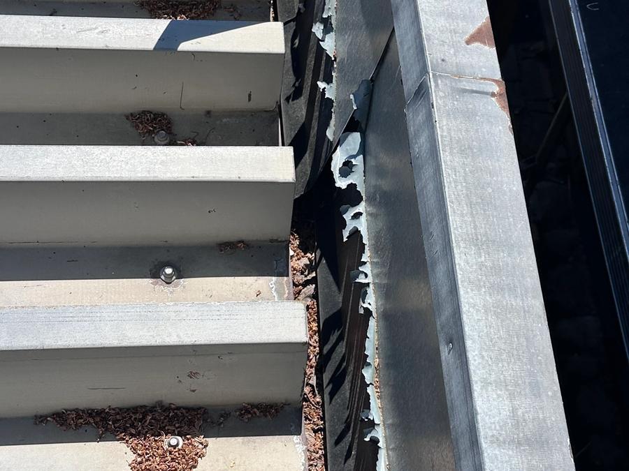 Detalj av kraftigt slitna fasadpaneler vid takanslutning, röta och rost