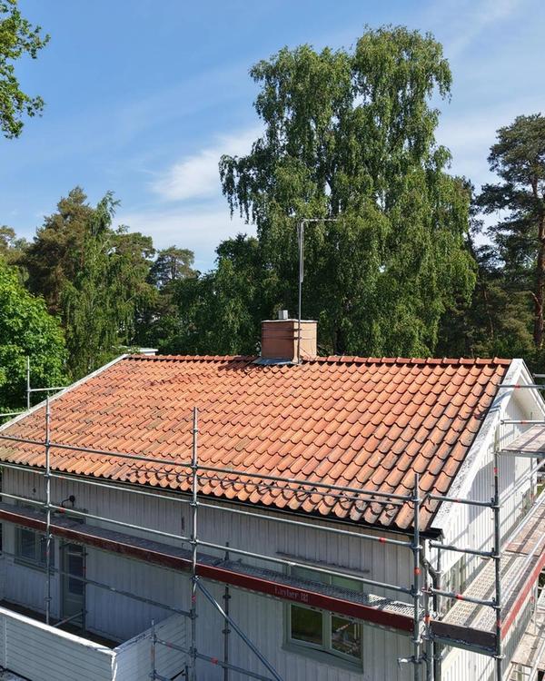 Gammalt slitet tegeltak med ställning monterat runt huset