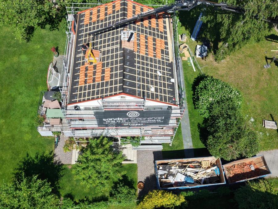 Kranarbete pågår och containern fylls med rivet takmaterial