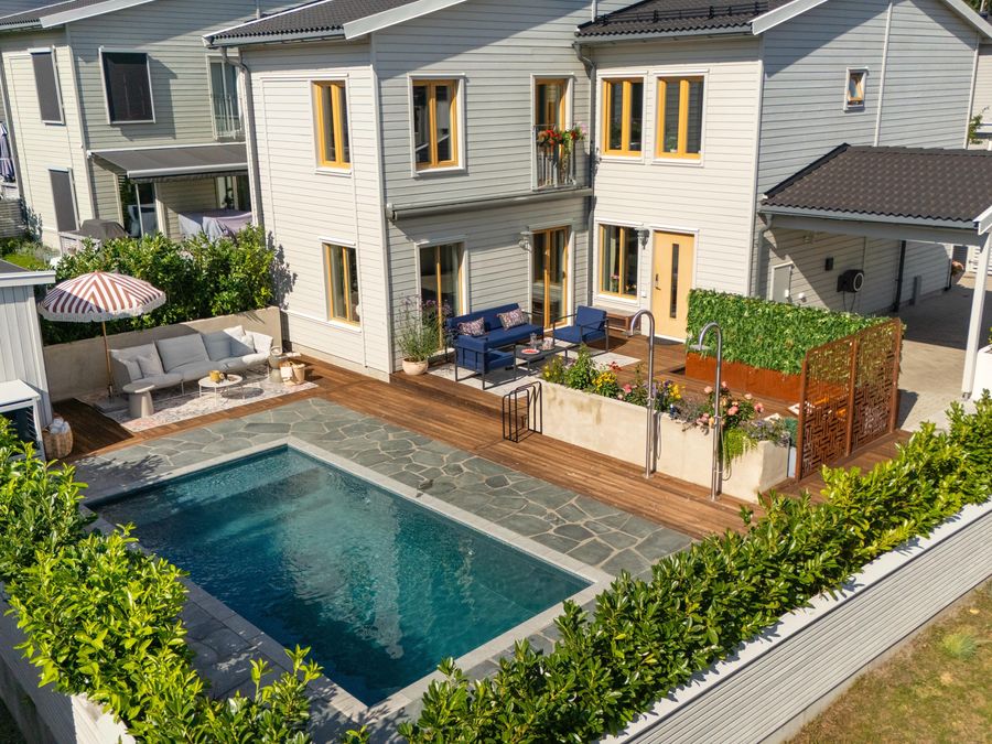 Pool och träaltan med loungemöbler mot husfasaden