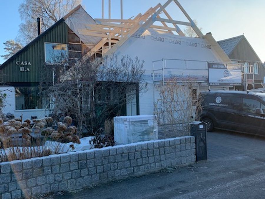Vitt hus med pågående takbygge, CASA H.A-skylt