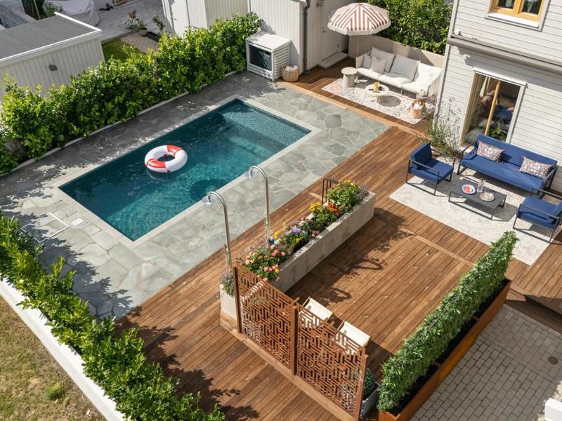 Nybyggd pool med natursten och träaltan på uteplats i Solna